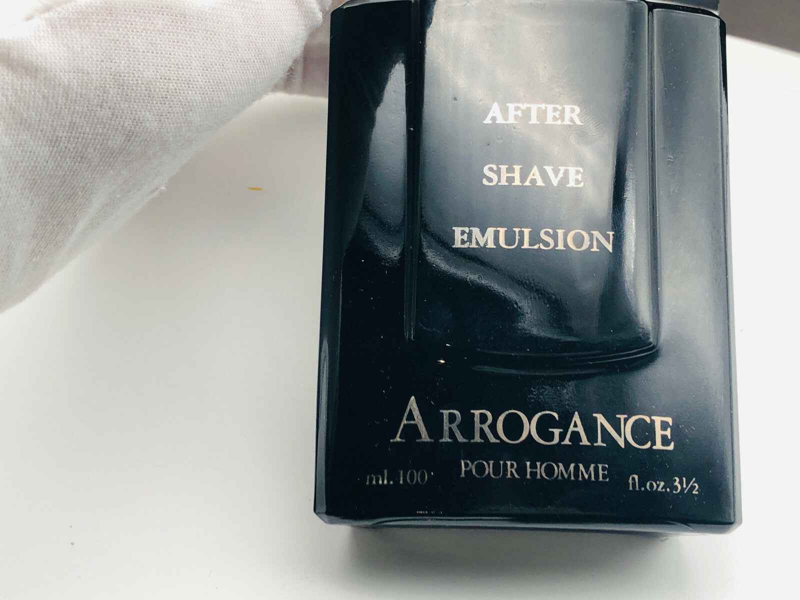 Emulsione dopobarba Arrogance Pour Homme in bottiglia nera elegante per un perfetto rituale di cura della pelle