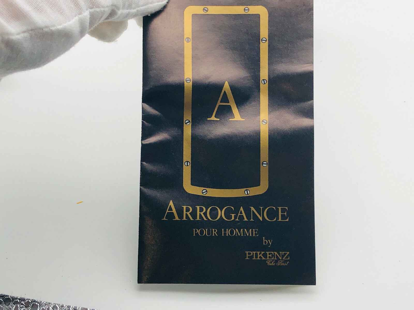 Etichetta del profumo Arrogance Pour Homme con design elegante e dettagli in oro