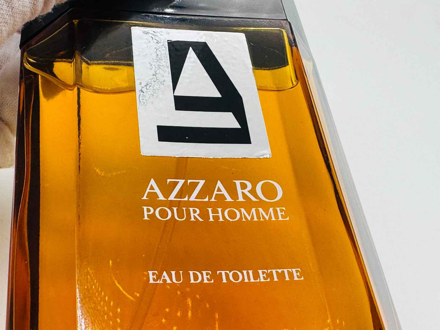Flacone di profumo Azzaro Uomo in vetro con etichetta elegante e liquido dorato