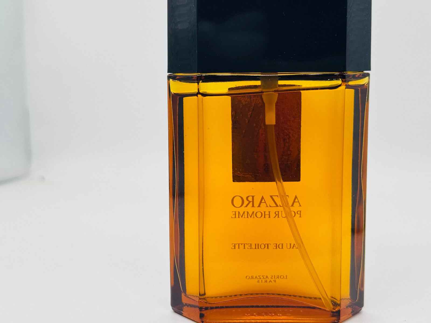 Profumo Azzaro Uomo in flacone trasparente con chiusura nera e etichetta dorata.