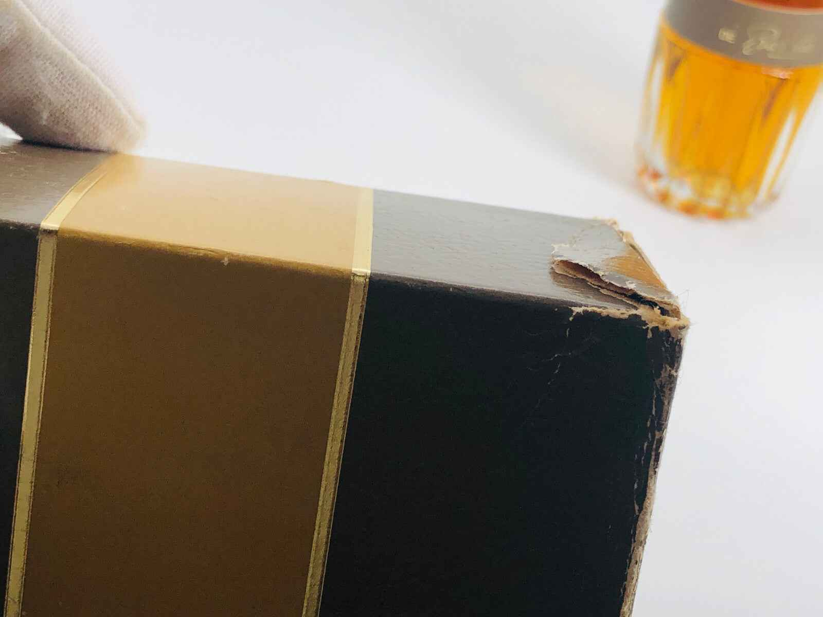 Scatola danneggiata di BARATTA VINTAGE Profumo con bottiglia sullo sfondo in tonalità dorate