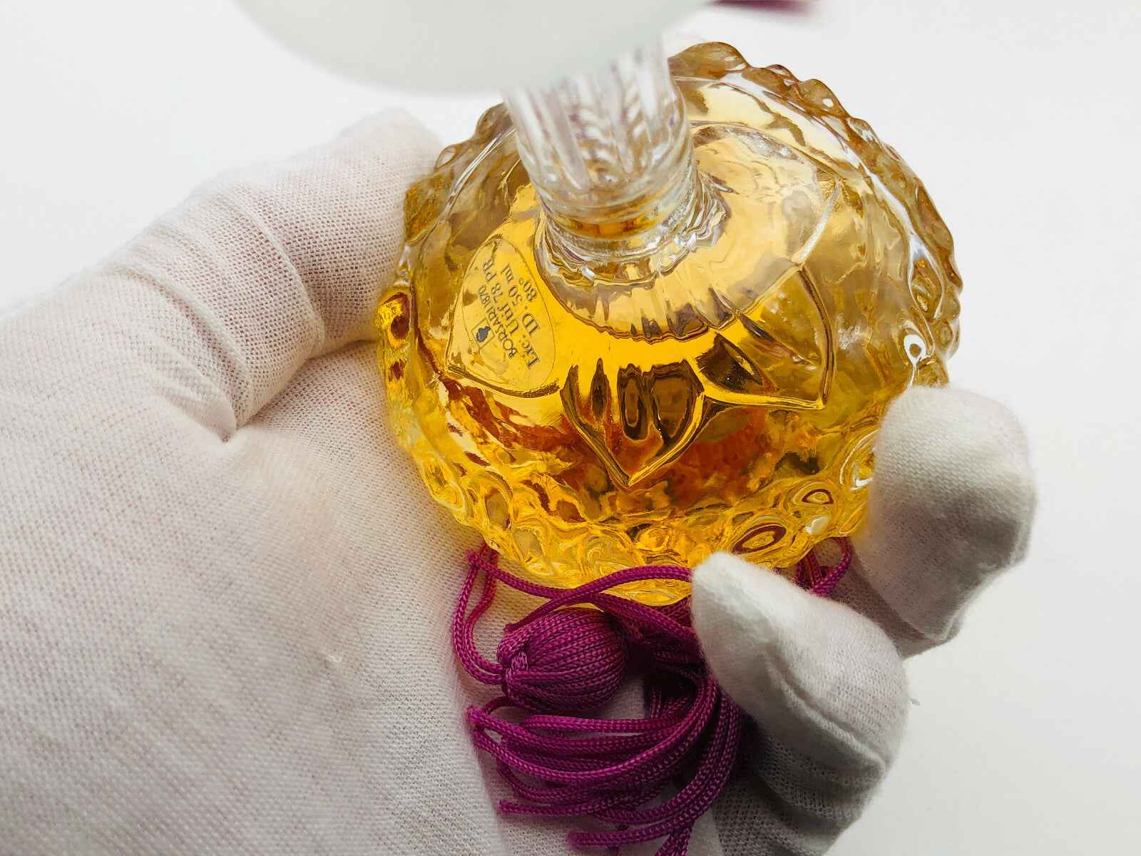 Flacone di profumo Vintage Borsari con design elegante e colore dorato, sorretto da una mano con guanto bianco
