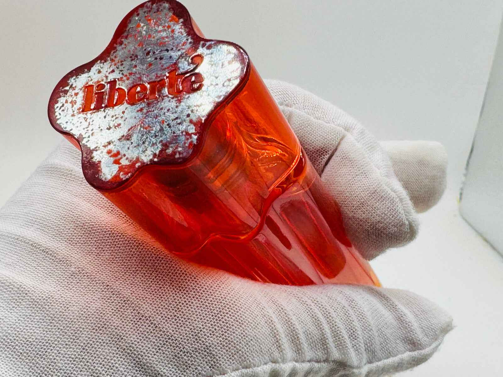 Flacone di profumo Cacharel Liberte Vintage in vetro rosso con design distintivo e logo elegante