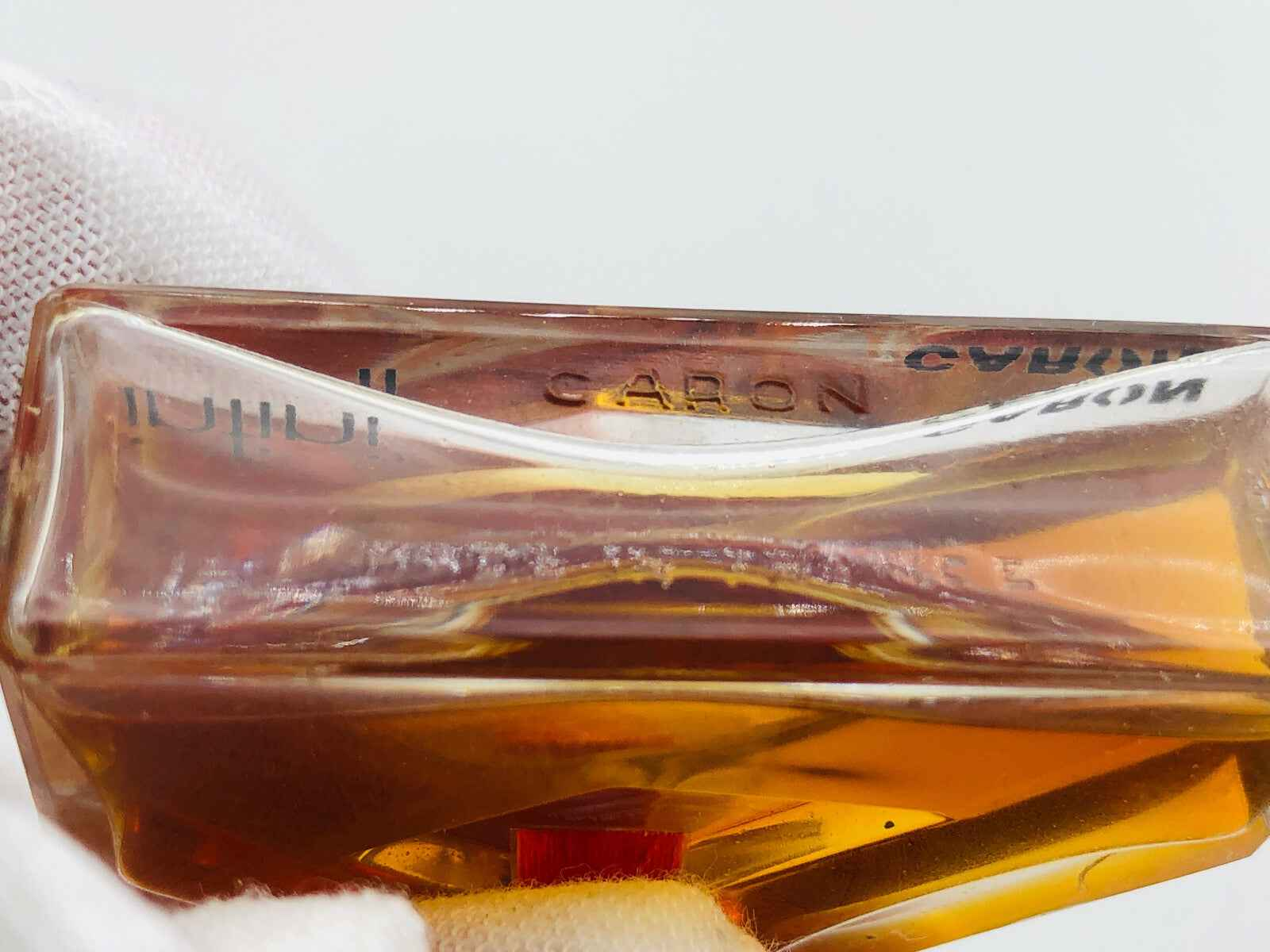 Flacone di profumo Infini Caron Parfum con un design elegante e colori caldi