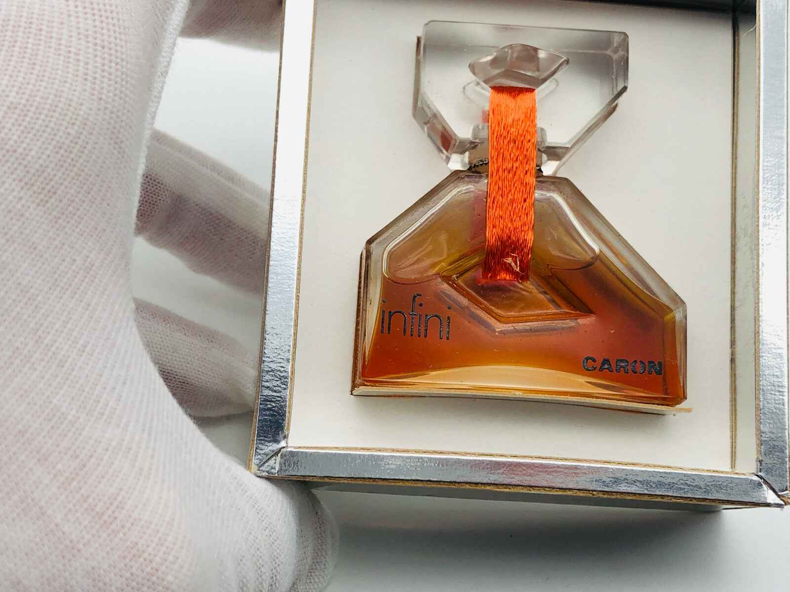 Profumo Infini Caron in bottiglia elegante con tappo trasparente e nastro arancione
