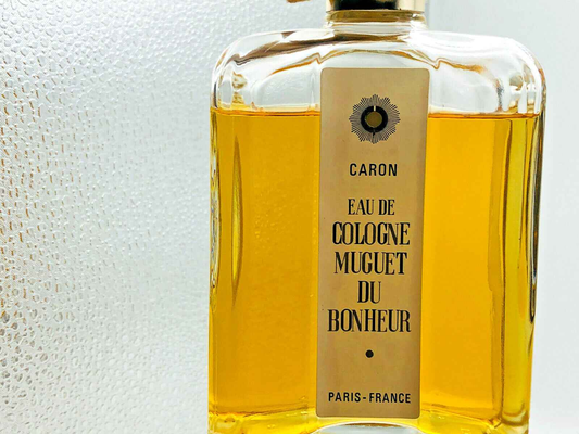 Bottiglia di profumo vintage Caron Eau de Cologne Muguet du Bonheur con etichetta elegante e liquido dorato