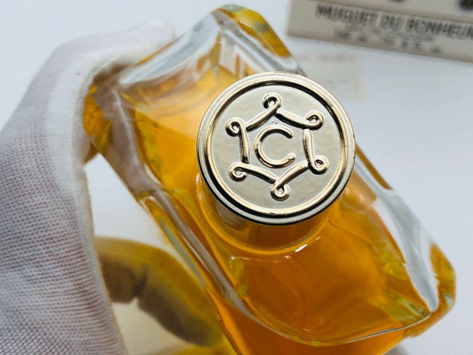 Flacone di profumo vintage Caron con tappo decorativo in oro e liquido giallo evidente