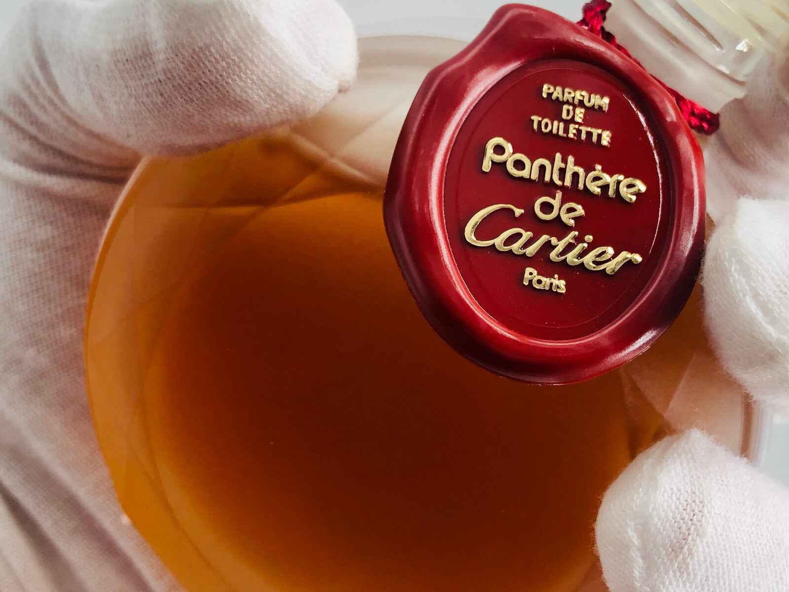 Flacone di profumo vintage Panthere Cartier con etichetta dorata e liquido ambrato