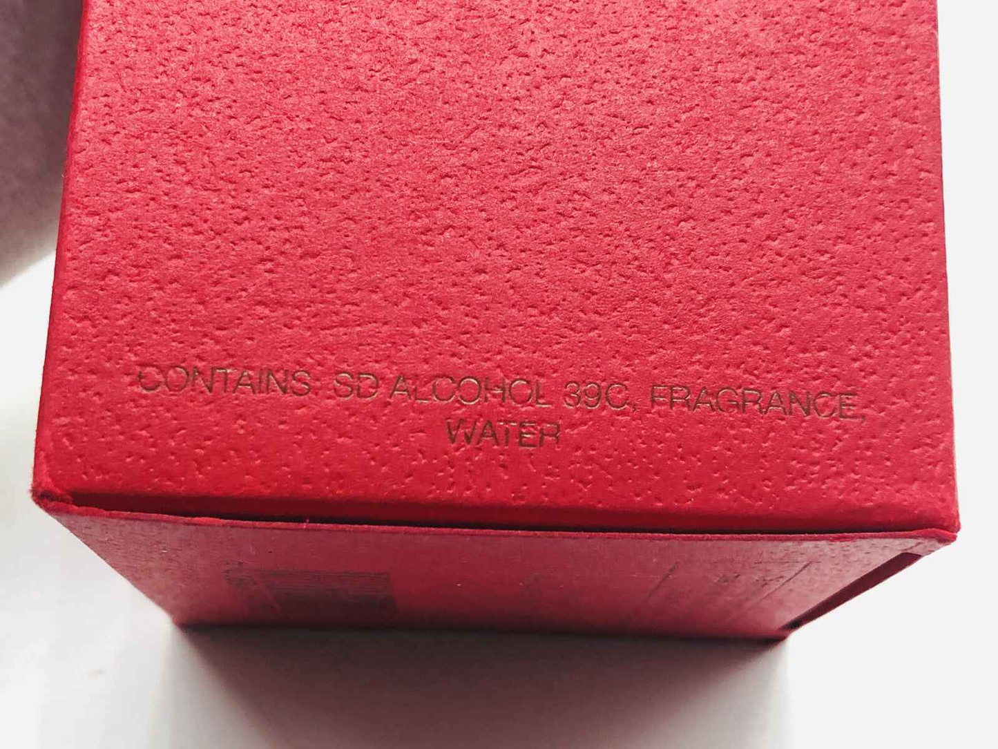 Scatola rossa di Claude Montana Parfum Homme con ingredienti in rilievo sulla superficie