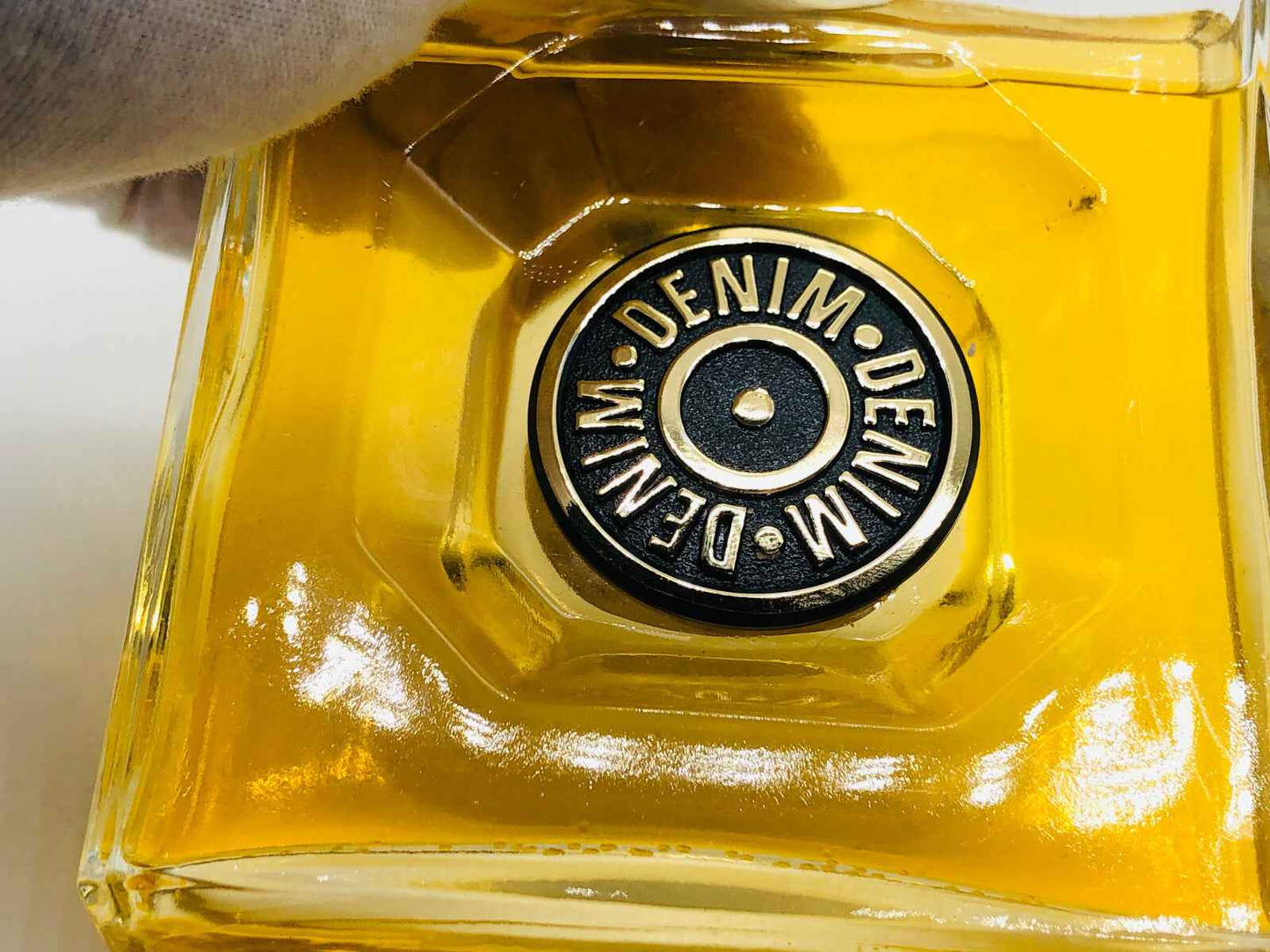 Flacone di Profumo Denim Original Vintage con tappo nero distintivo e liquido dorato