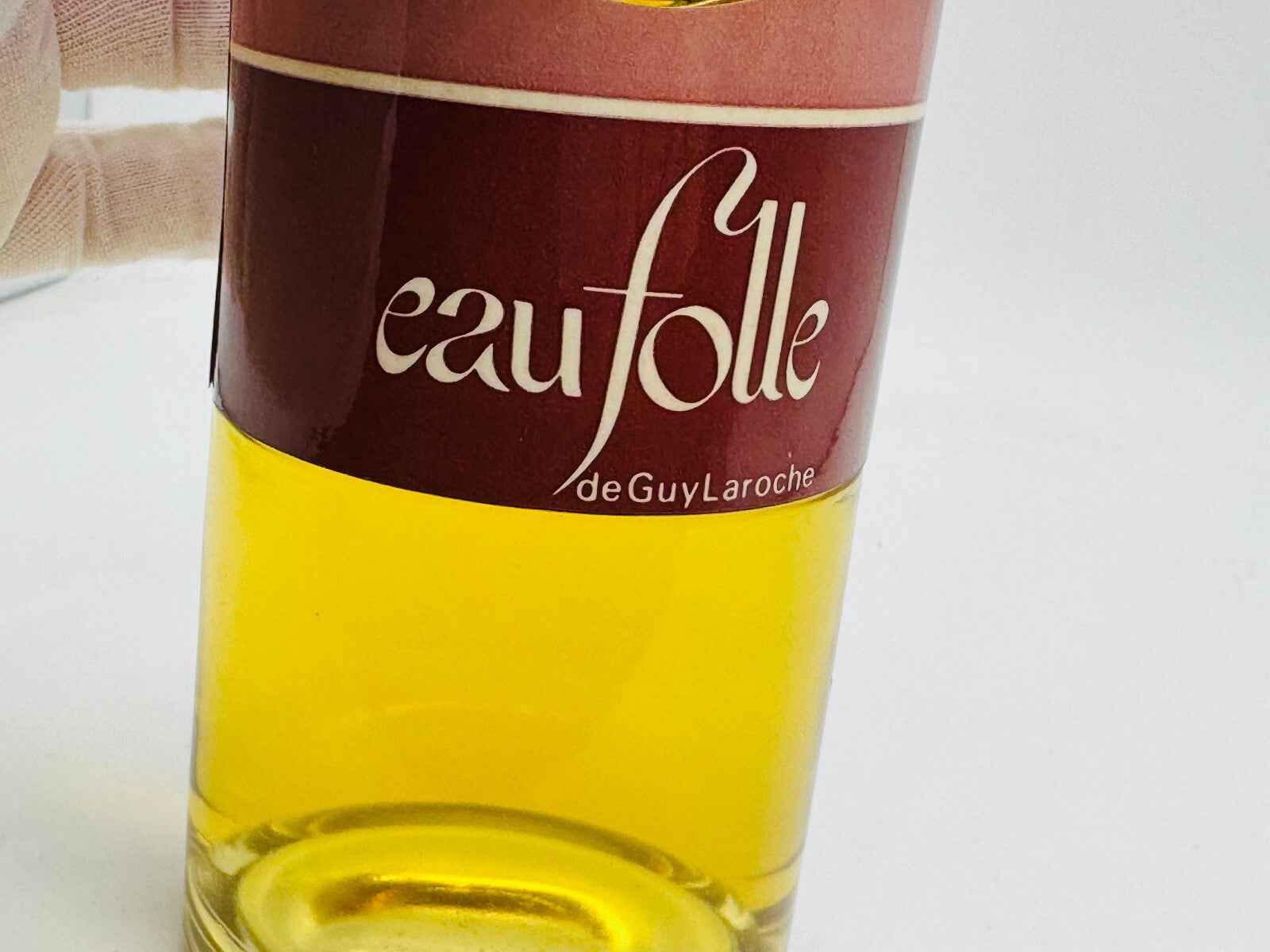 Flacone vintage di Eau Folle Laroche con etichetta rossa e liquido giallo, simbolo di eleganza e stile
