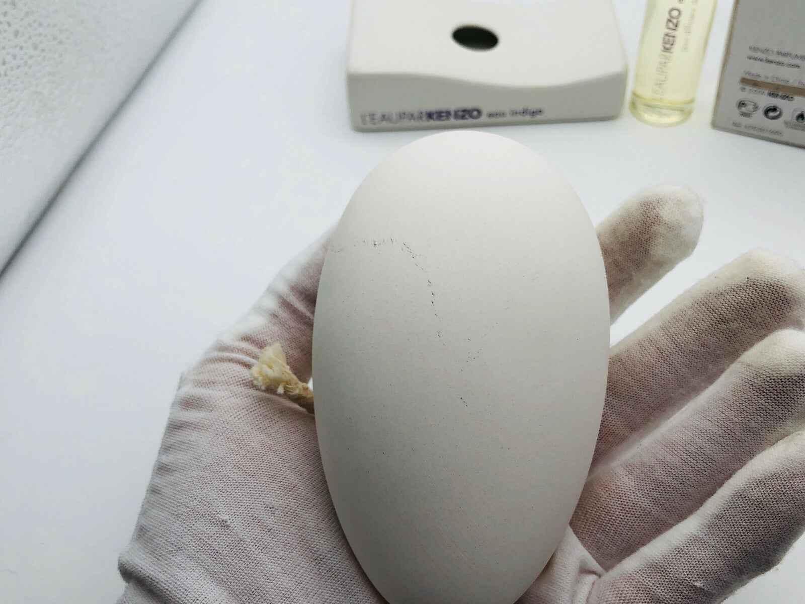 Flacone L'Eau Par Kenzo Indingo Femme con design ovale, in mano, in ambientazione minimalista