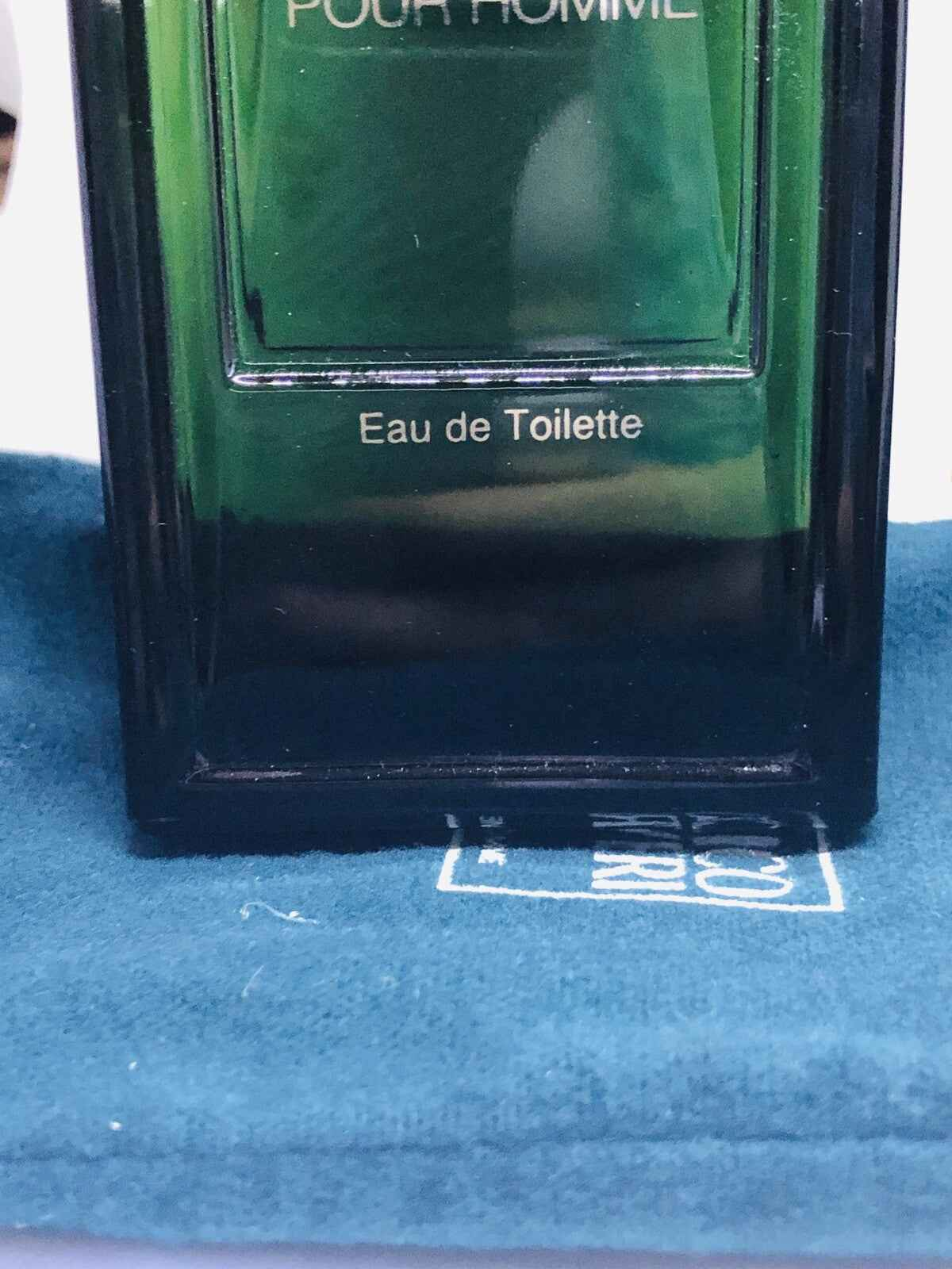 Flacone di profumo Enrico Coveri Pour Homme con etichetta Eau de Toilette su un panno blu