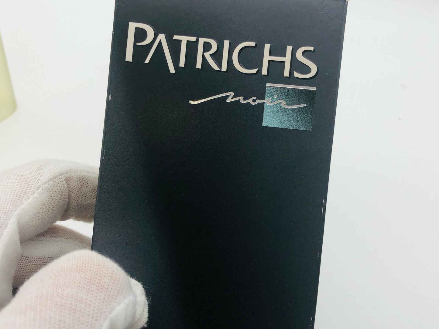 Scatola di profumo Patrichs Noir Vintage con logo elegante su sfondo scuro