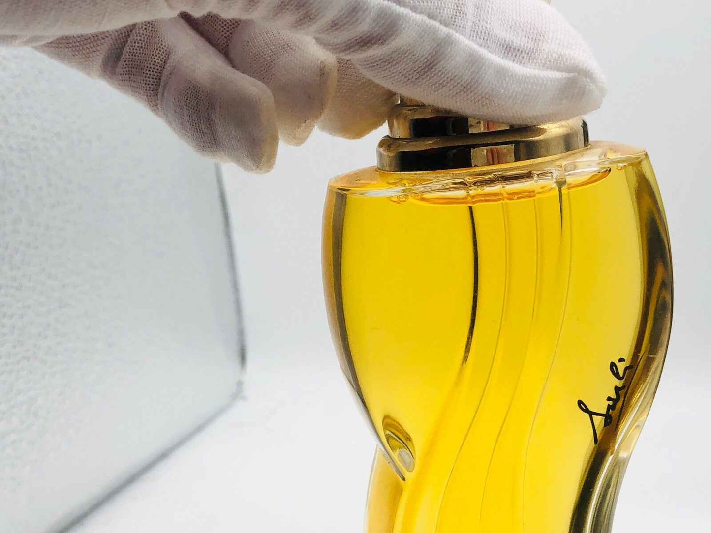 Flacone di profumo Fausto Sarli con tappo dorato e forma sinuosa, lucido e elegante