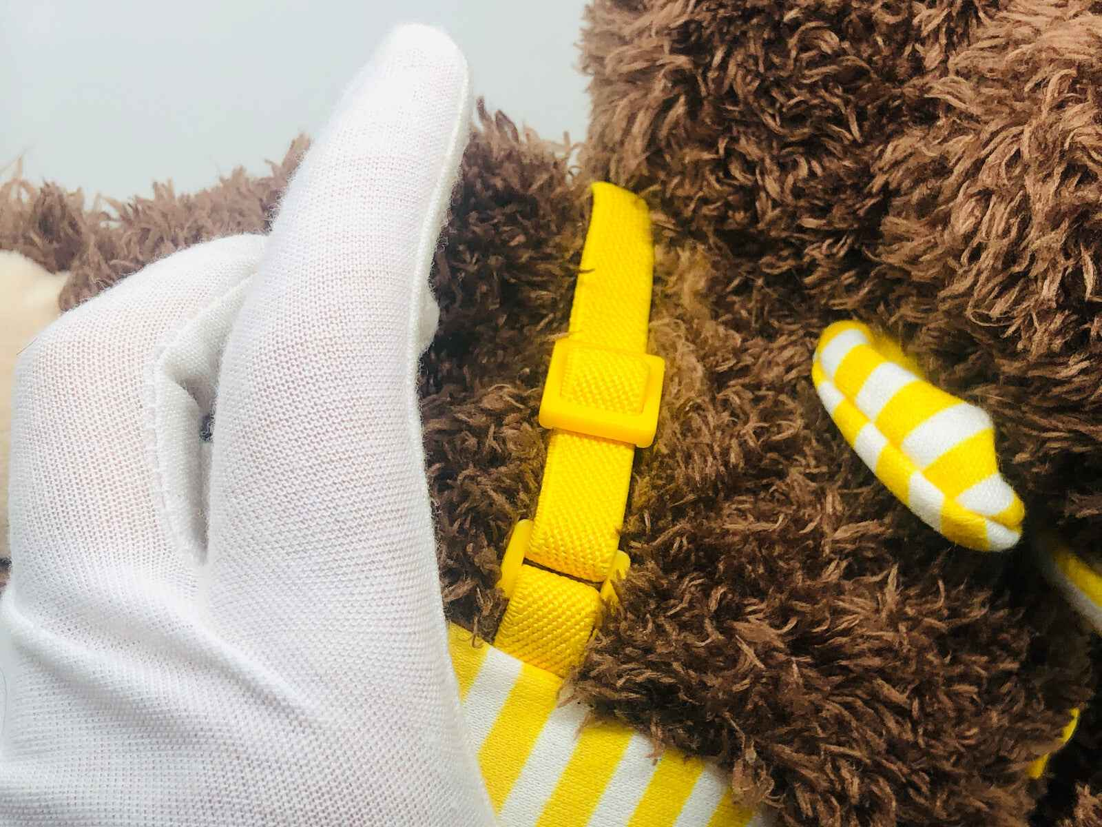 Peluche marrone con dettagli gialli e strisce per bambini, ideale per regali speciali