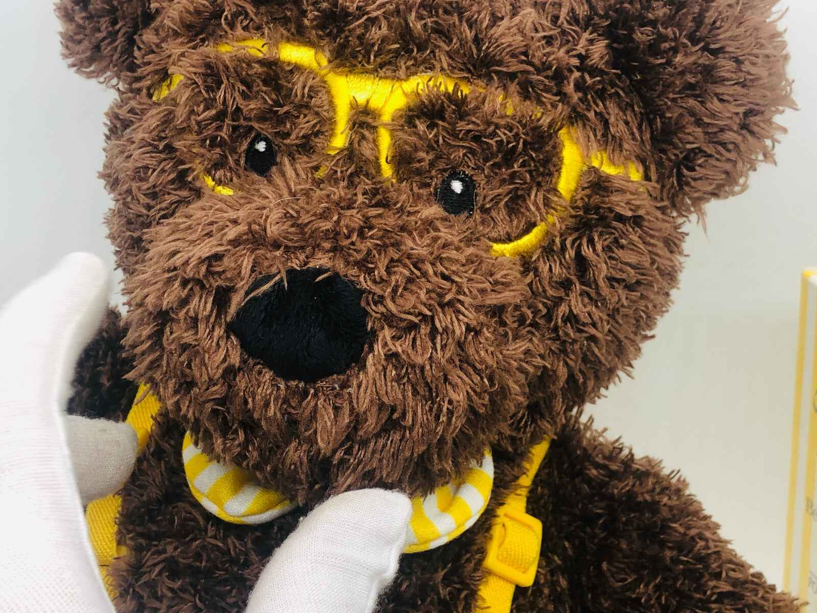 Orsetto di peluche marrone con occhiali gialli e pettorina, perfetto per i fan di Giorgio Beverly Hills Homme