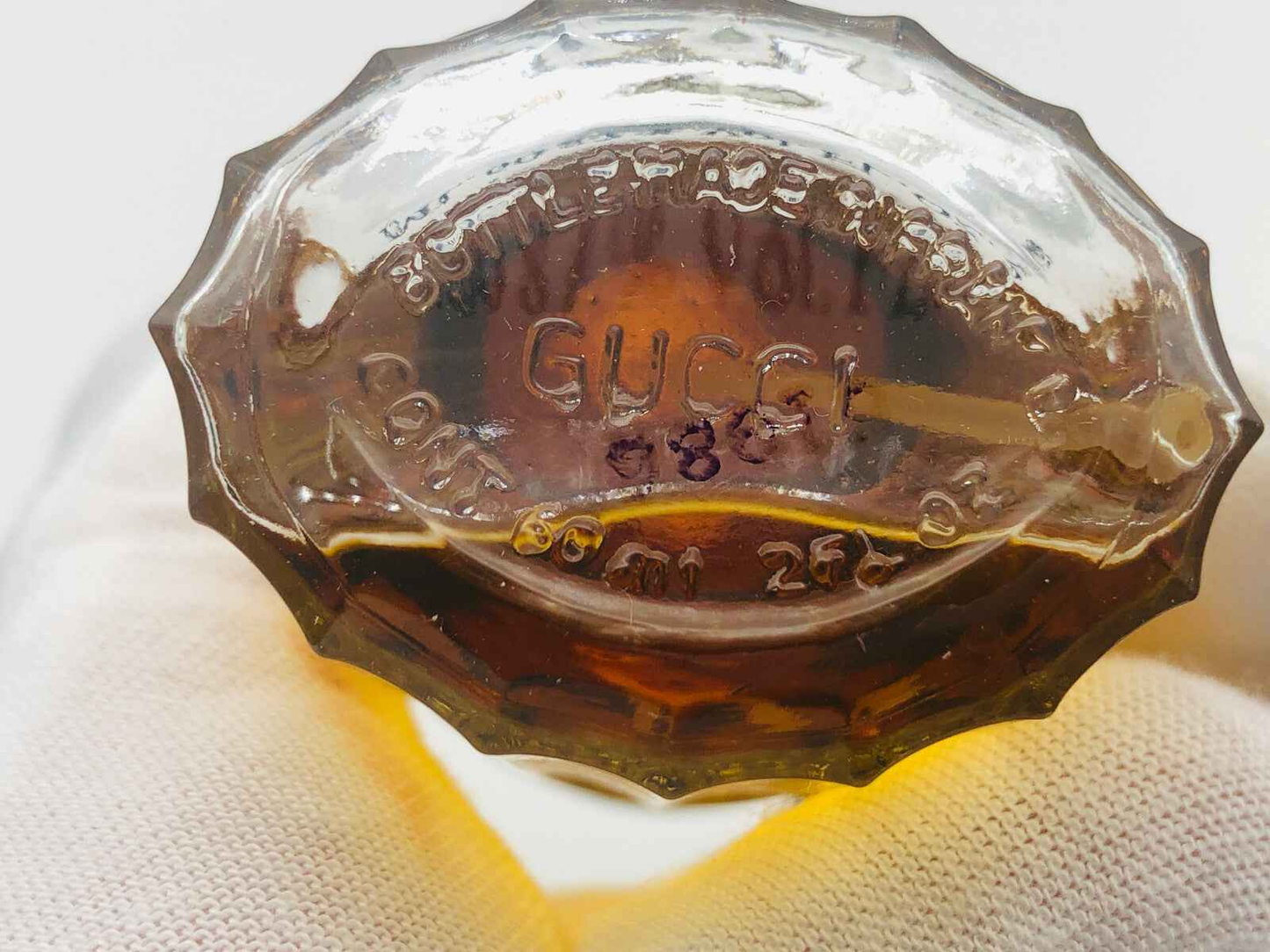 Bottiglia di PROFUMO EAU DE GUCCI VINTAGE con etichetta in rilievo sul fondo e design elegante