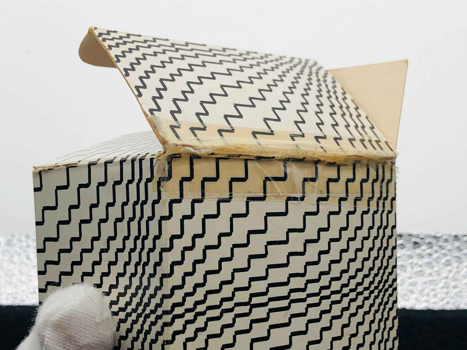Scatola di Guerlain Mitsouko Parfum con design a zigzag in bianco e nero, aperta per mostrare l'interno