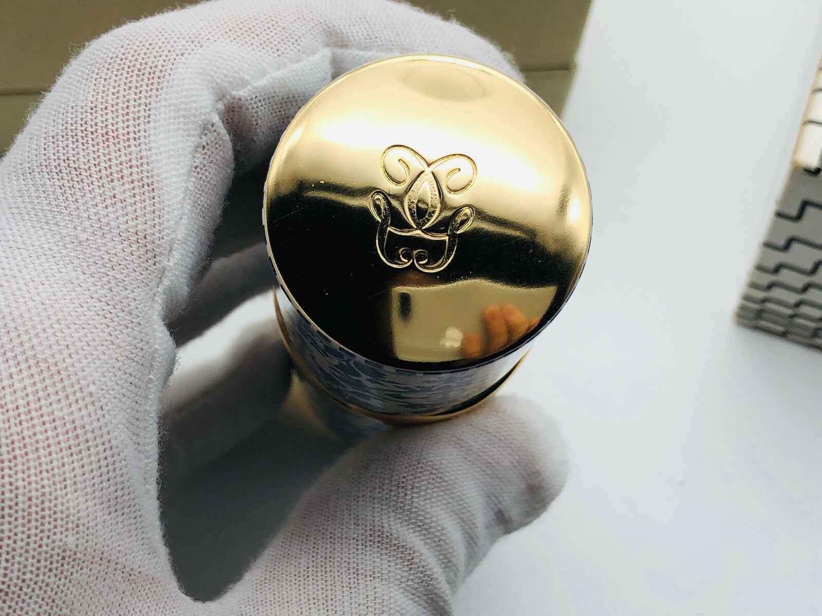Tappo dorato del profumo Guerlain Mitsouko Parfum con logo distintivo sulla parte superiore