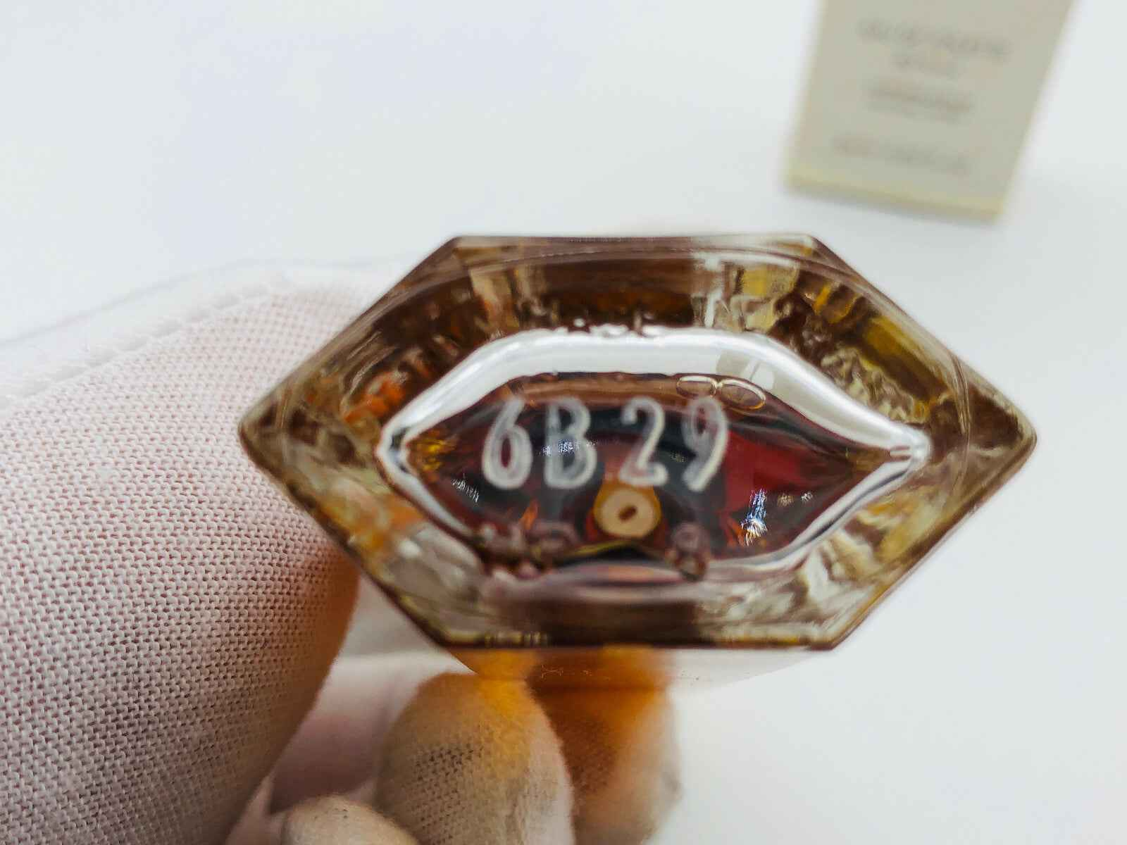 Dettaglio del fondo del flacone di profumo Jean Louis Scherrer con numero di serie visibile