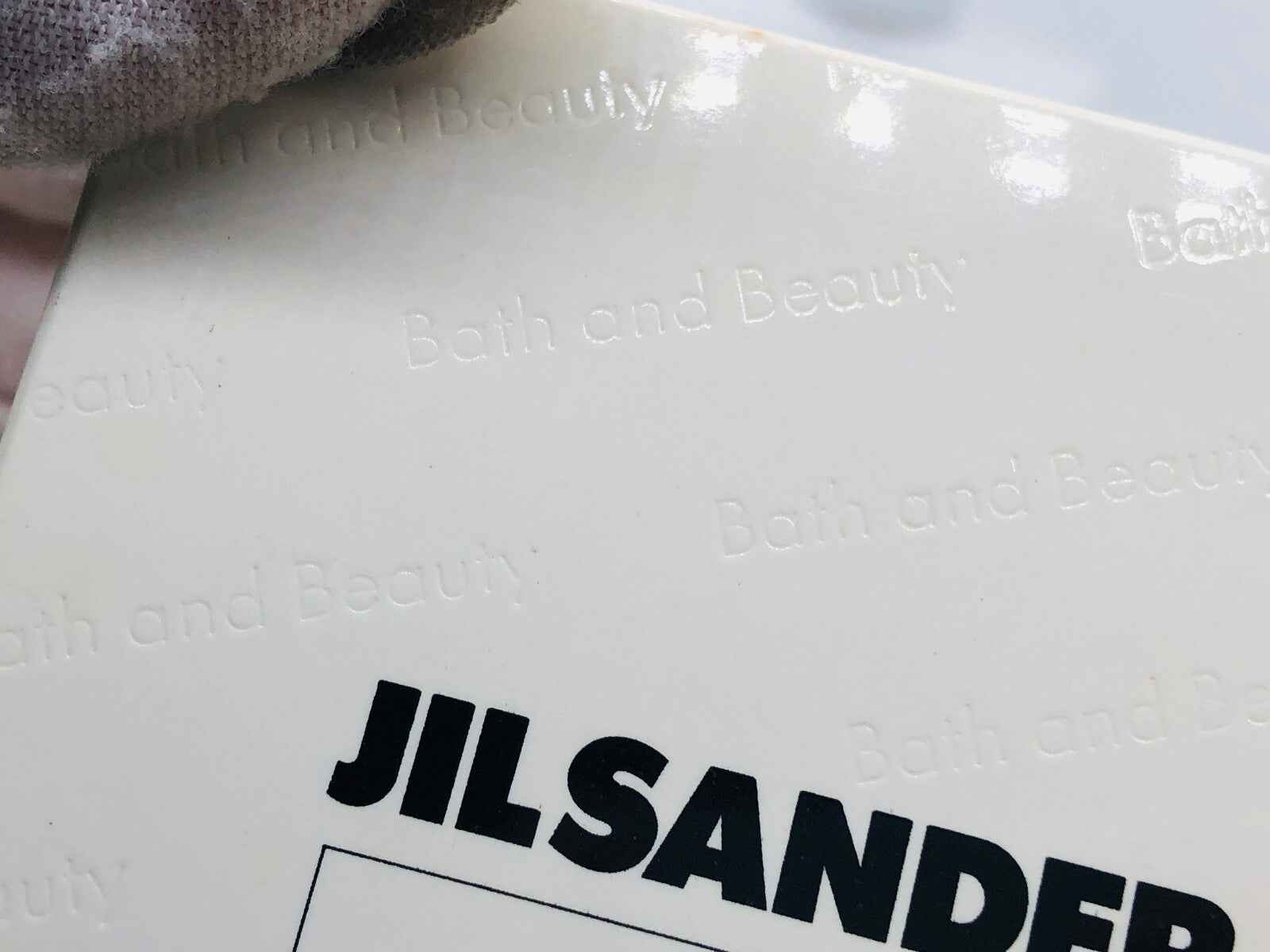 Dettaglio della confezione di Jil Sander Bath And Beauty con logo in rilievo sulla superficie