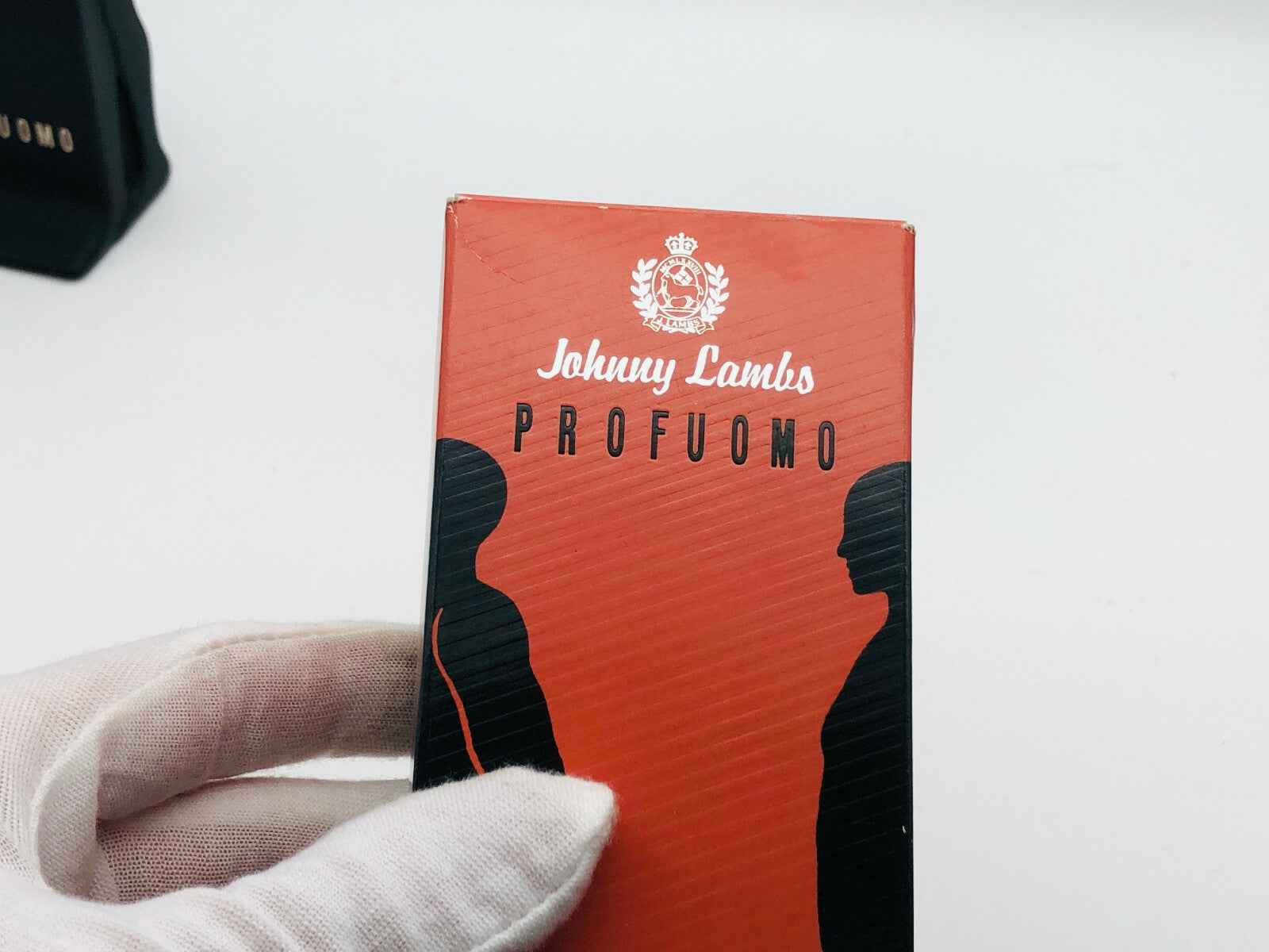 Scatola di profumo Johnny Lambs con design elegante e silhouette nere su sfondo rosso