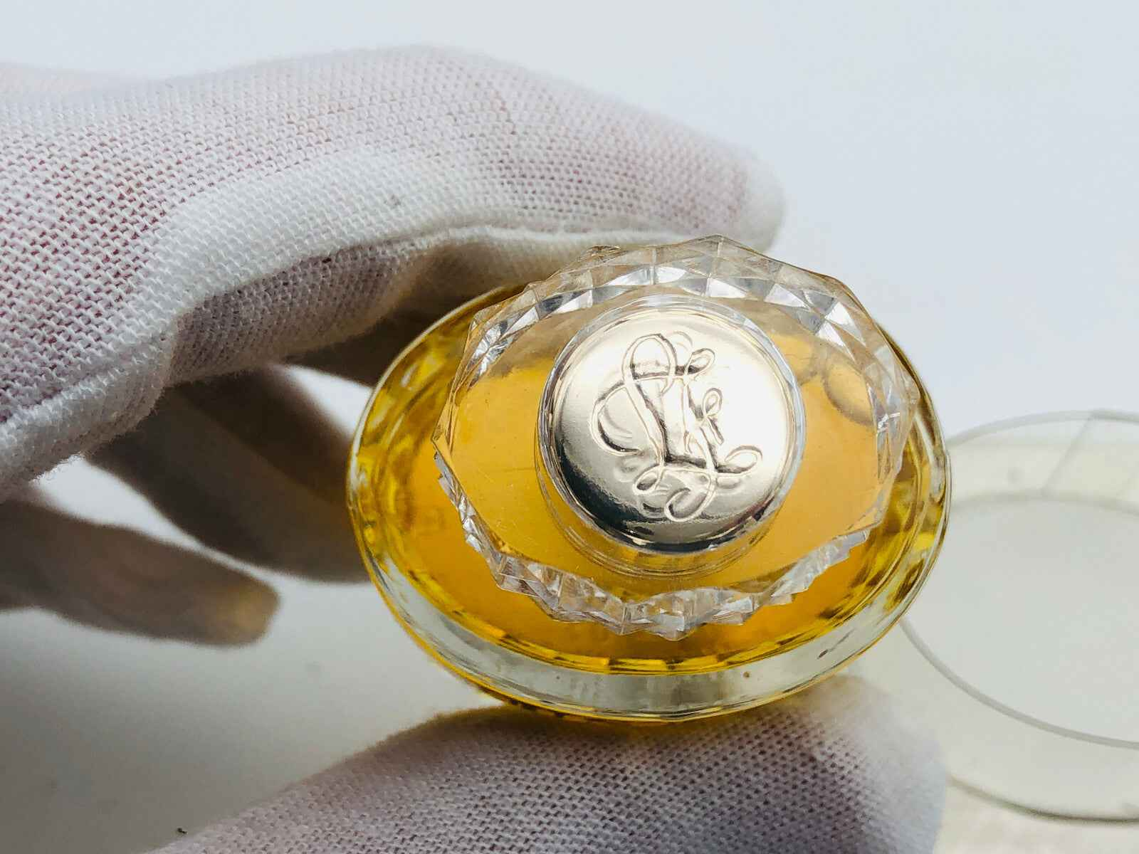 Flacone di profumo Justine Louis Feraud con tappo elaborato e liquido giallo dorato