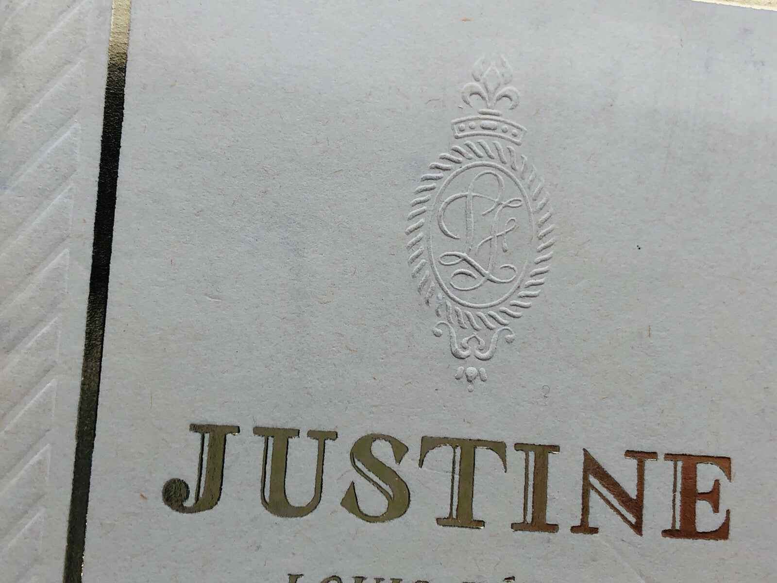 Logo Justine Louis Feraud in rilievo su carta con dettagli dorati ed eleganti