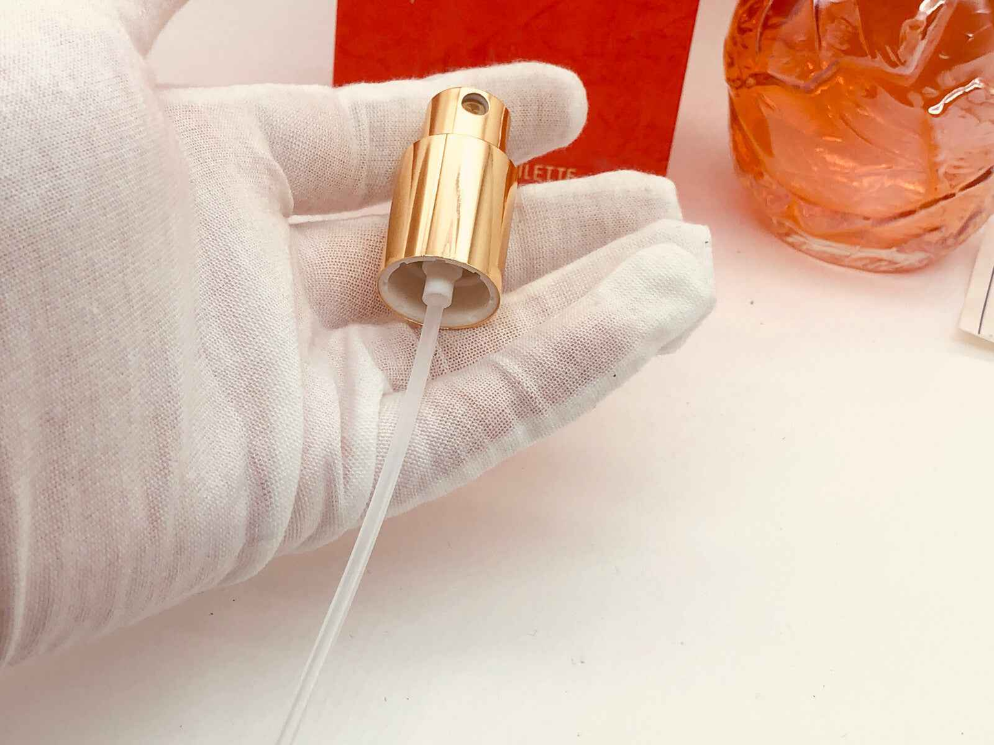 Flacone di profumo Kenzo Kashaya con vaporizzatore dorato e scatola rossa sullo sfondo