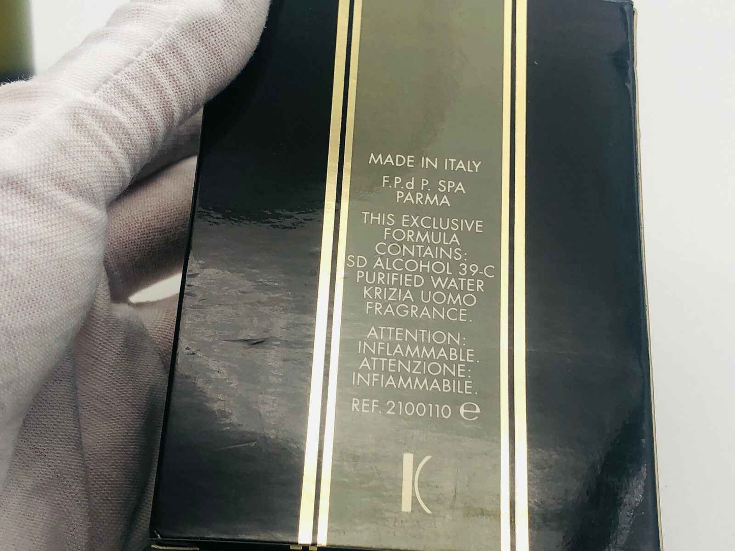 Confezione nera del Profumo Krizia Uomo Vintage con dettagli dorati tenuta da mano con guanto bianco