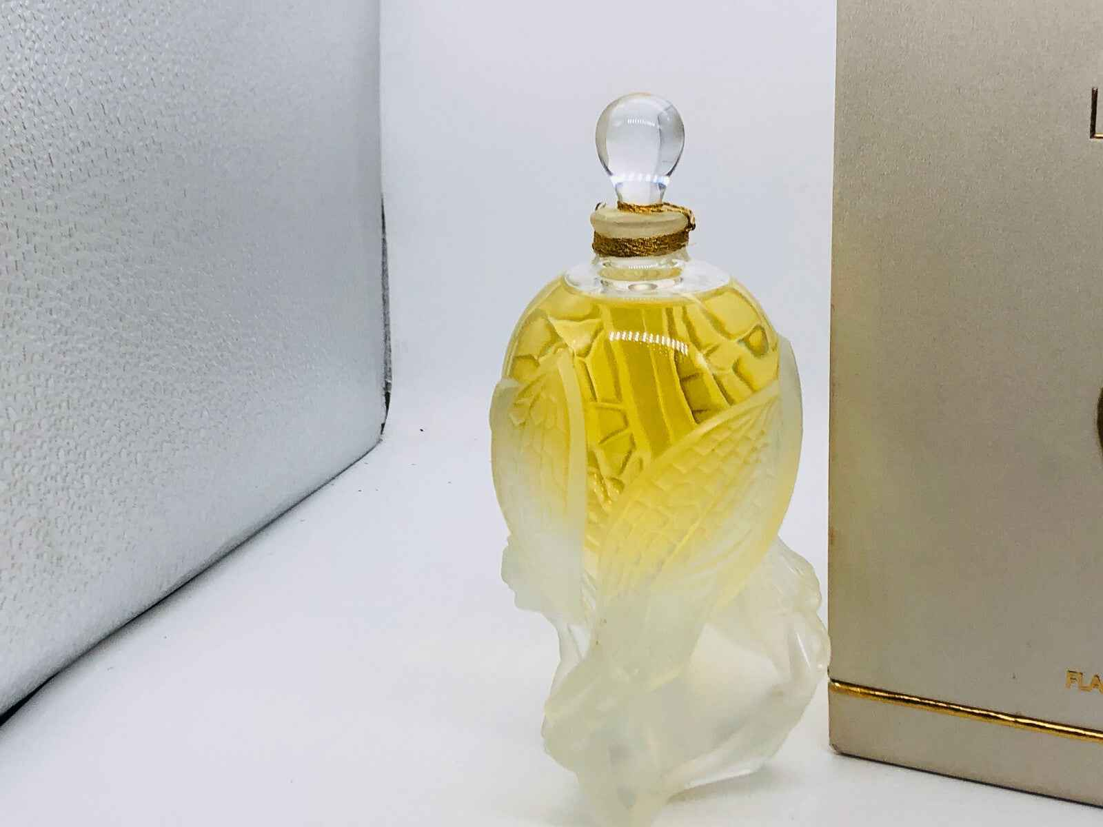 Bottiglia di profumo Lalique Les Elfes con tappo sferico e design elegante, contenente profumo dorato