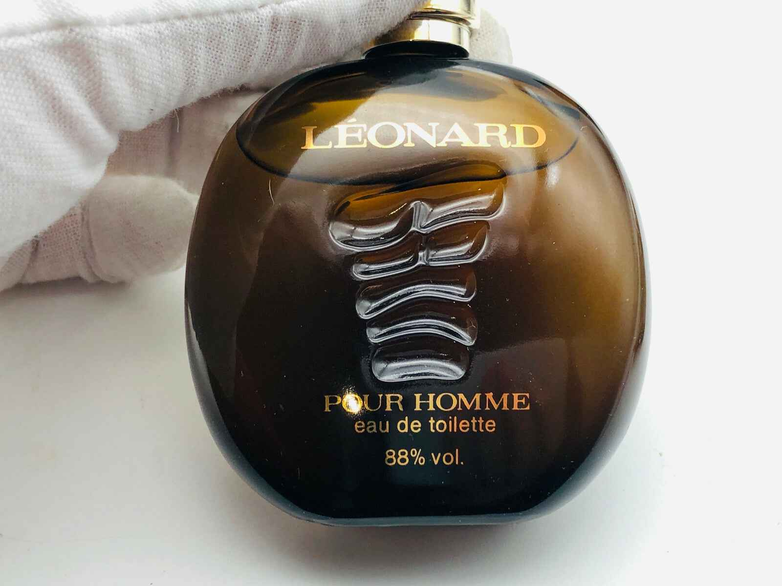 Bottiglia di profumo Leonard Pour Homme in vetro marrone con etichetta dorata ed elegante design