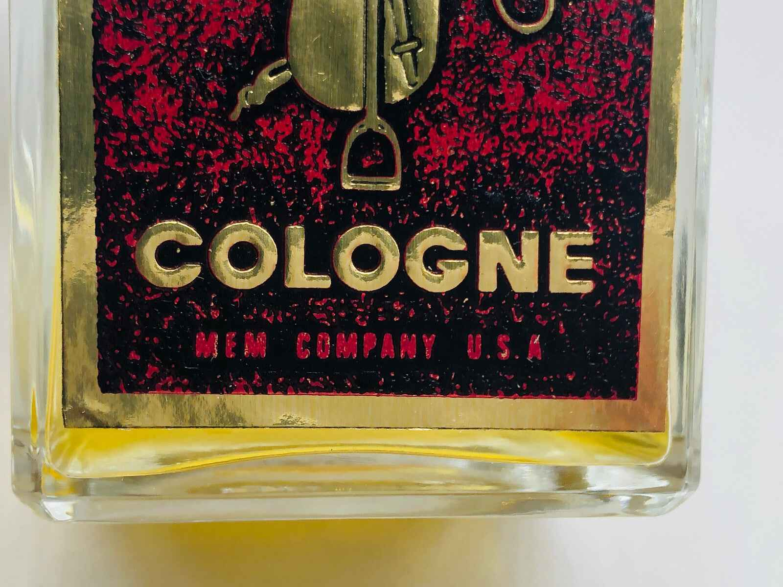 Flacone di colonia MEM Company English Leather con etichetta dorata su sfondo rosso