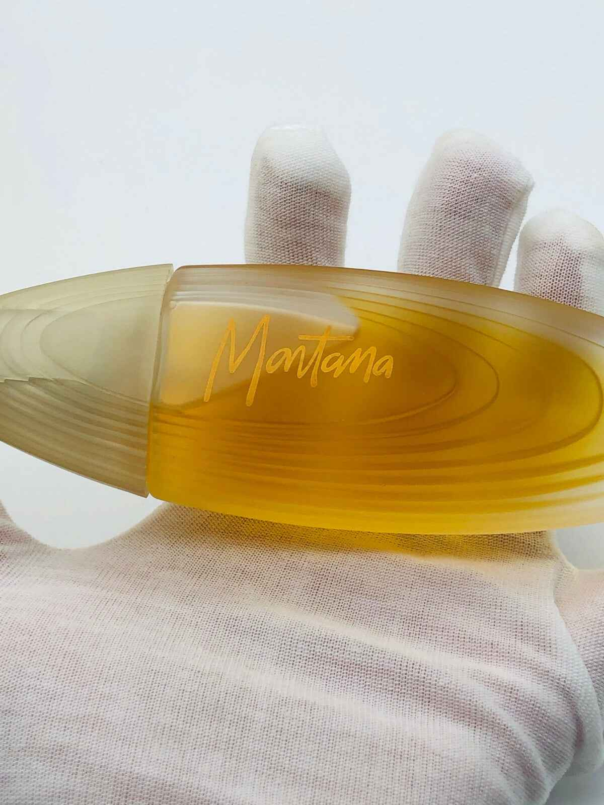 Flacone di Montana Parfum D'Elle con design elegante e tonalità dorata, tenuto in mano con guanto bianco