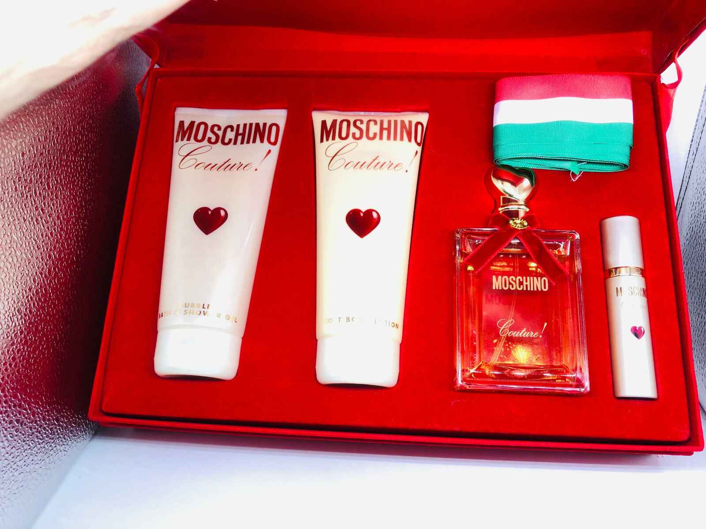Set profumo Moschino Couture Vintage con profumo e crema corpo su fondo rosso elegante