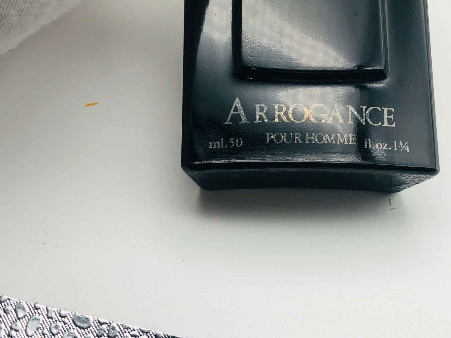 Bottiglia nera da 50 ml di profumo Arrogance Pour Homme su sfondo bianco