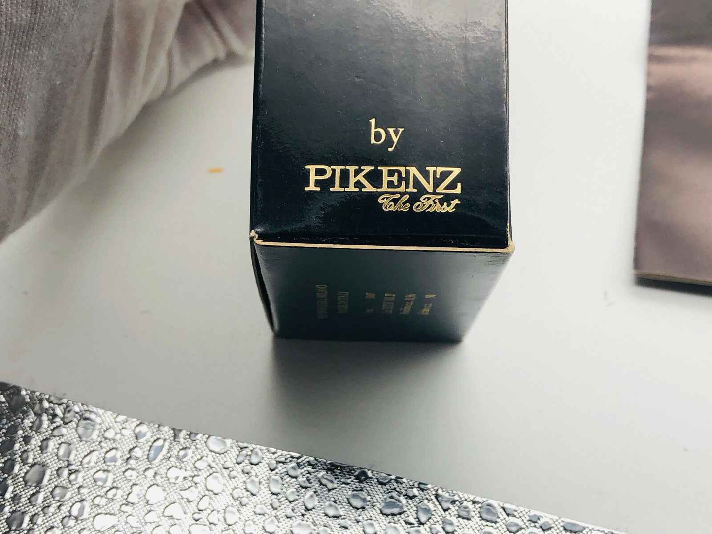 Confezione nera elegante del profumo Arrogance Pour Homme di Pikenz con logo dorato
