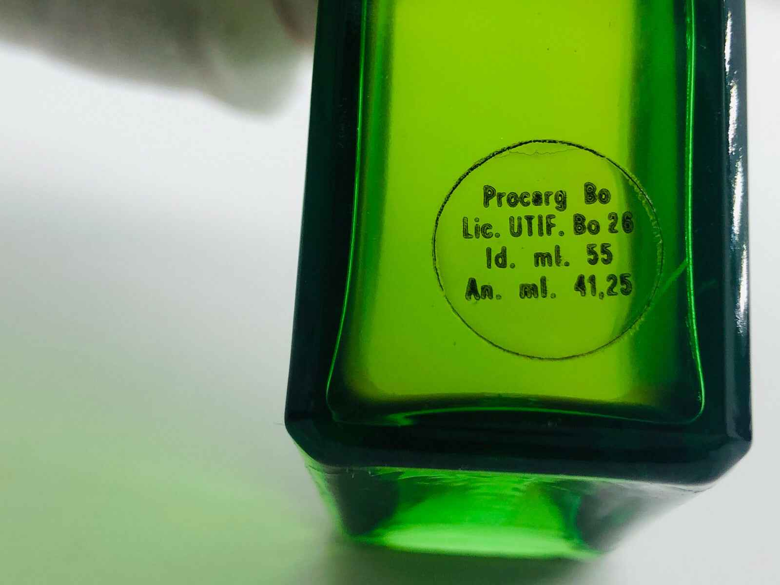 Dettaglio del fondo di una bottiglia di profumo Procarg Sherwood Vintage con etichetta verde.