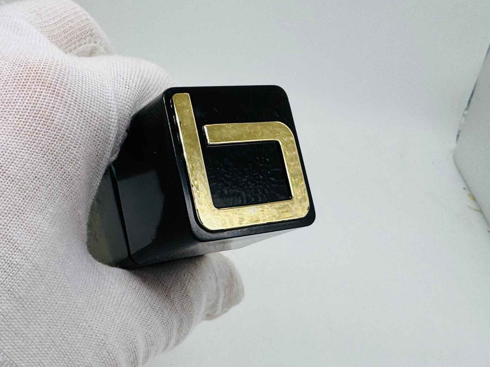 Dettaglio della bottiglia di profumo Jacques Bogart con tappo nero e logo dorato