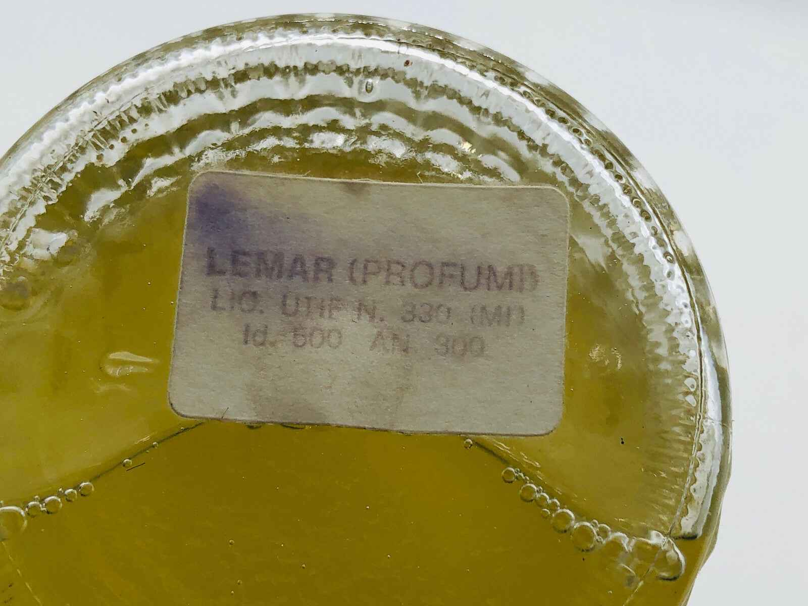 Flacone di profumo Lemar Colonia con etichetta chiara e liquido dorato all'interno