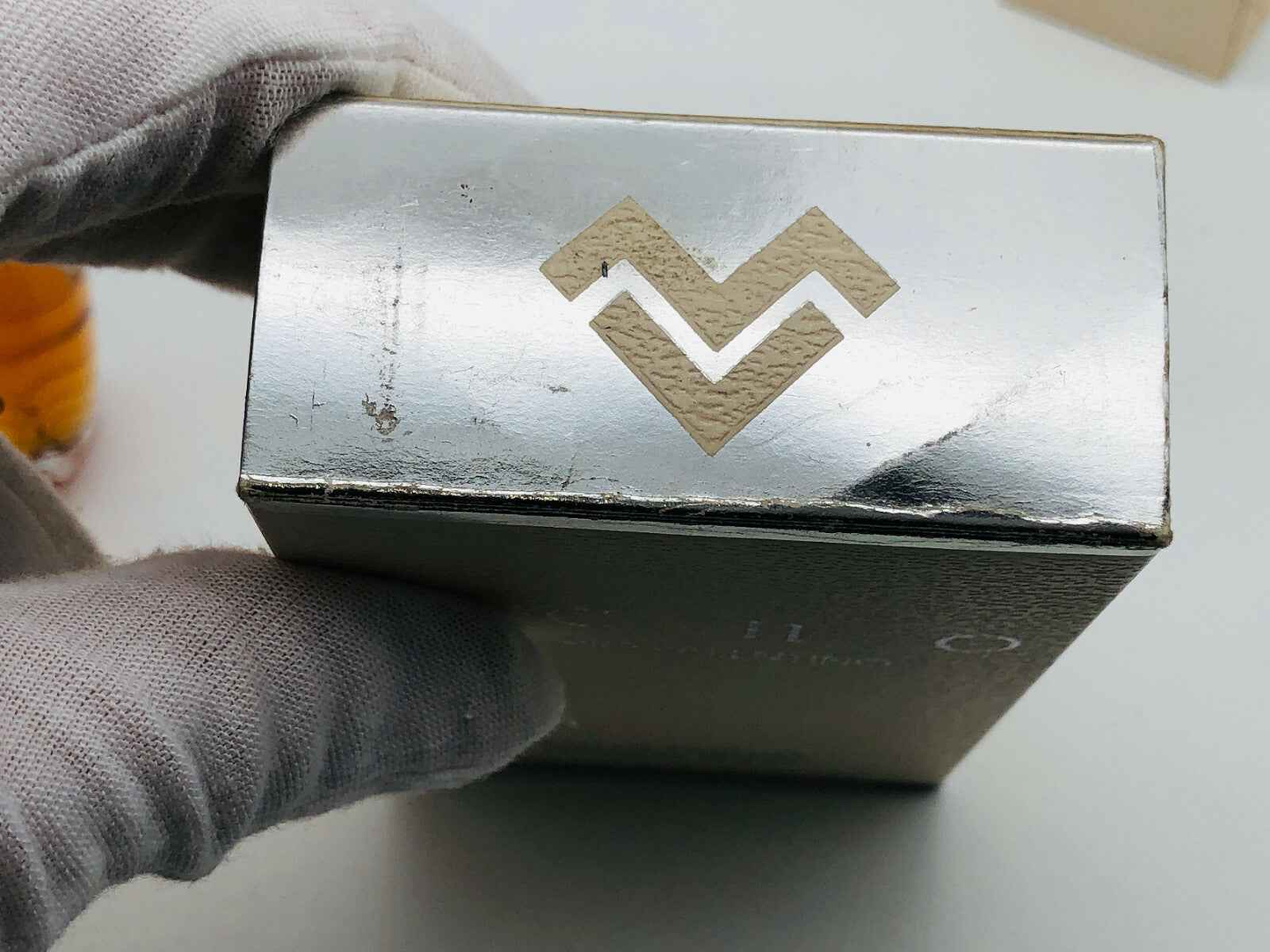 Scatola del profumo Mario Valentino Echo con logo in rilievo su fondo metallico