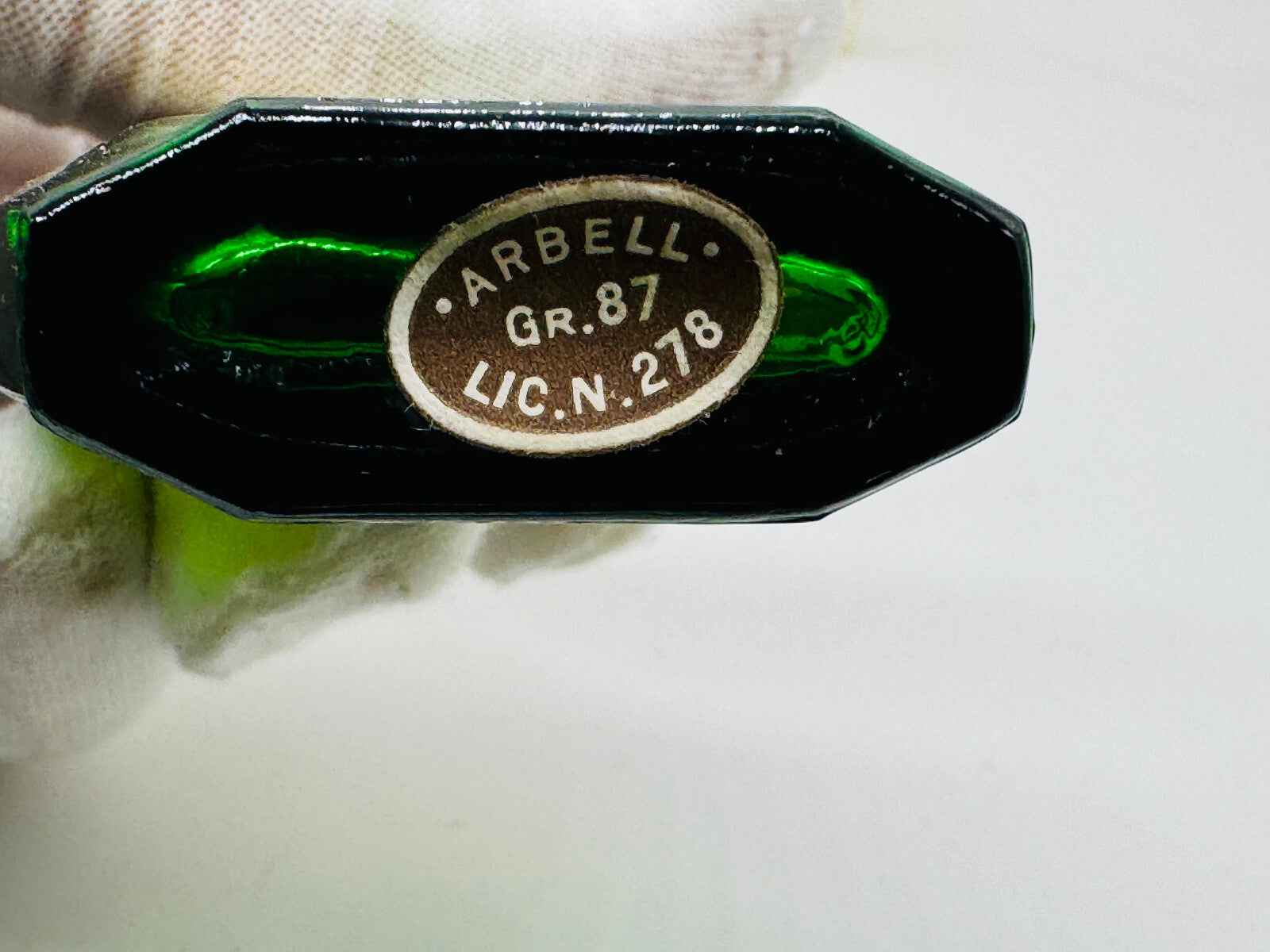 Fondo del flacone di profumo Pino Arbell con etichetta identificativa di provenienza