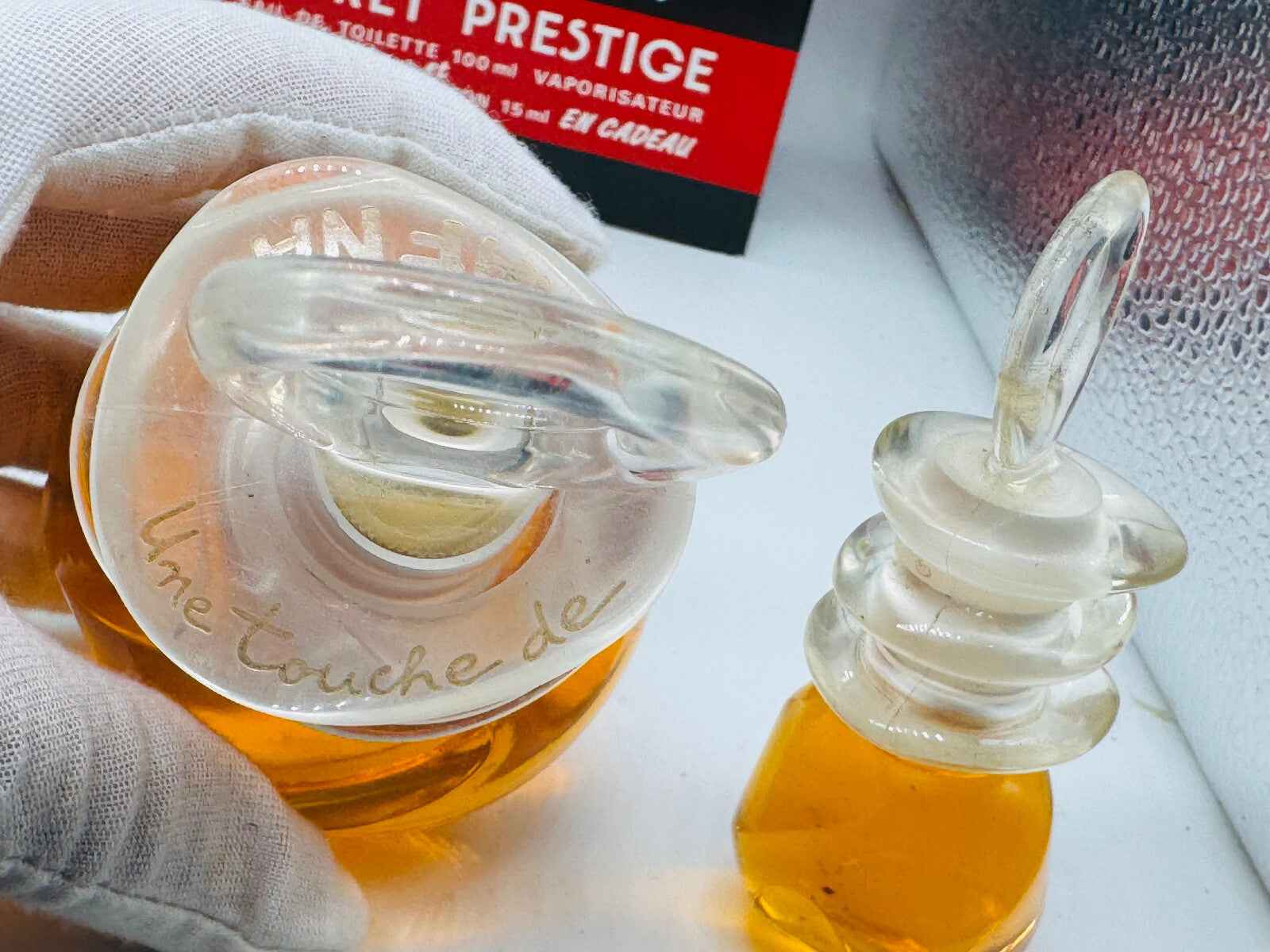 Flacone di profumo Un Touche Naf Naf con design elegante e tonalità ambrate, accompagnato da un mini flacone.