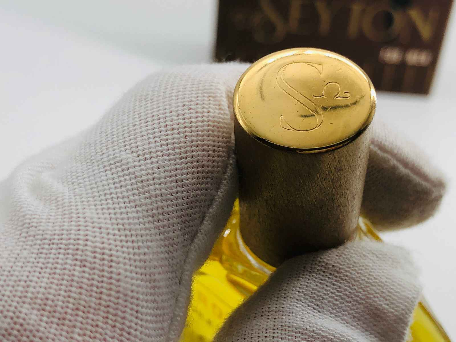 Dettaglio del tappo dorato di un flacone di profumo Vic Seyton con logo inciso