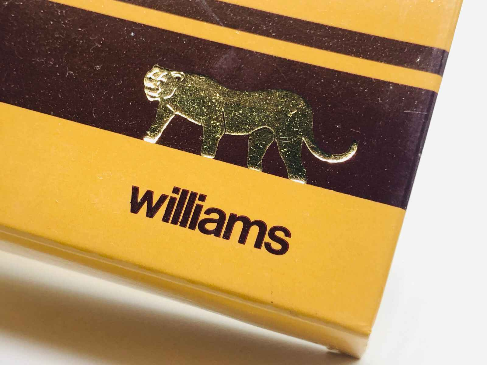 Scatola del profumo Williams Savane con logo di un leone in confermazione dorata su sfondo giallo