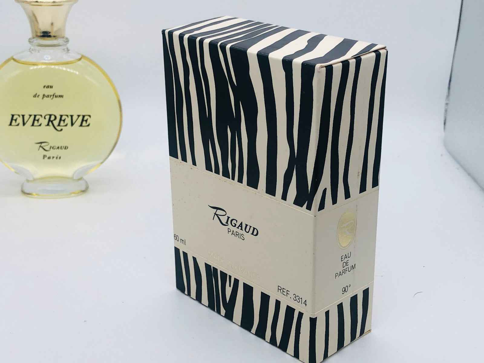 Scatola del profumo Rigaud Evereve Vintage con design a righe e flacone di profumo sullo sfondo