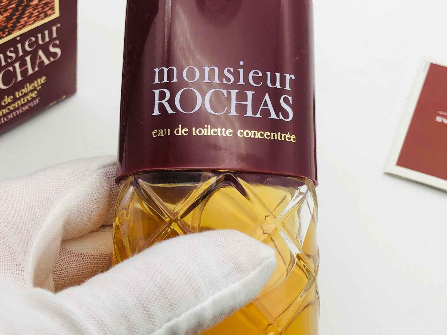 Flacone di profumo Rochas Monsieur Vintage con tappo decorativo e liquido dorato.
