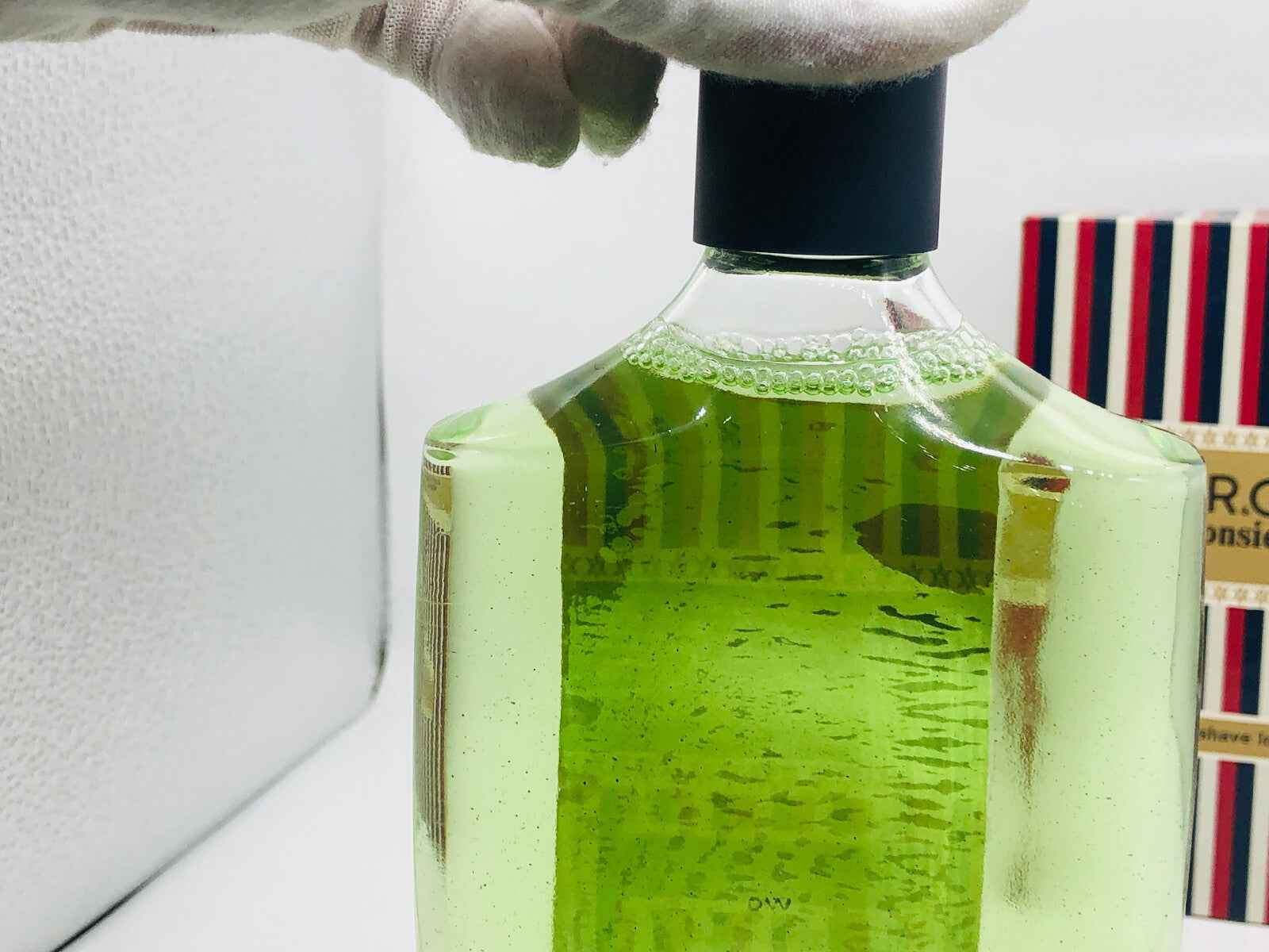 Flacone di profumo Monsieur Roger Gallet con liquido verde brillante e tappo blu elegante