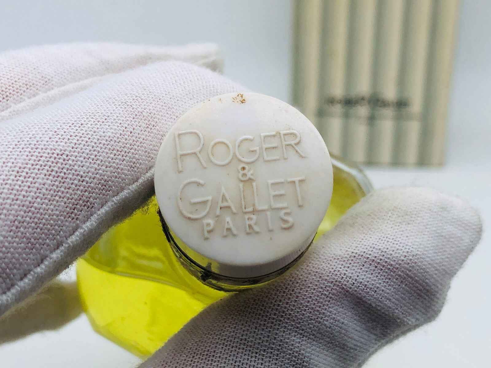 Tappo del profumo Roger & Gallet Vintage con logo in rilievo e sfondo di confezione elegante